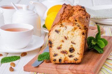 Limonlu kek kurutulmuş cranberries ve beyaz ahşap zemin üzerine kuru üzüm ile