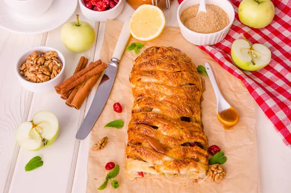 apple pie with dried cherries, walnuts, lemon zest and cinnamon on white wooden background