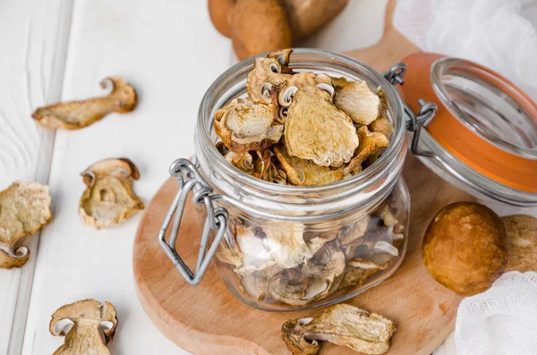 Dried forest mushrooms in a glass jar on a wooden background