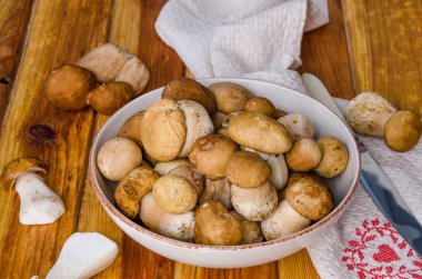 Koyu ahşap arka plan üzerinde bir kapta taze orman beyaz mantar