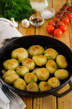 Sarımsak ve dereotu ile dökme demir tavada Kızarmış Genç Patates. Rustik stil.