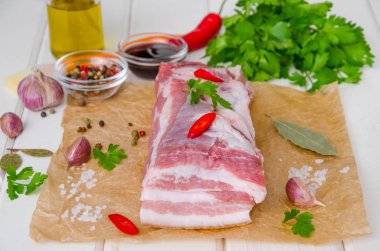 Beyaz ahşap arka plan üzerinde tuz, biber, sarımsak, biber, soya sosu ve bal ile çiğ taze domuz göbeği.