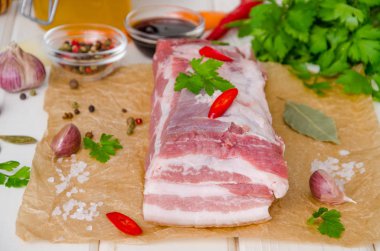 Beyaz ahşap arka plan üzerinde tuz, biber, sarımsak, biber, soya sosu ve bal ile çiğ taze domuz göbeği.