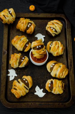 Halloween mumyalar - siyah bir arka plan üzerinde eski bir fırın tepsisine baharatlı domates sosu ile hamur sarılmış köfte. Cadılar Bayramı partisi için fikir.