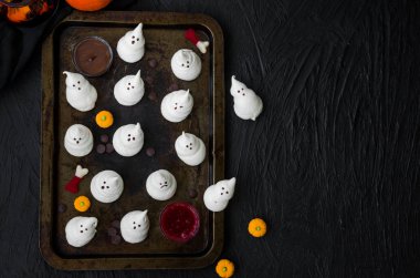 Siyah bir arka plan üzerinde eski bir fırın tepsisine çikolata ve berry soslar ile Ghosts Halloween Beingues. Cadılar Bayramı partisi için gıda fikri.