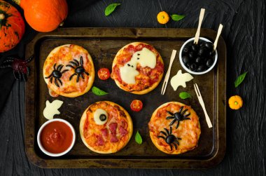 Siyah bir arka plan üzerinde Halloween Mini Pizza Monsters. Örümcek Pizza, Hayalet Pizza, Canavar Pizza. Cadılar Bayramı partisi için gıda fikri.