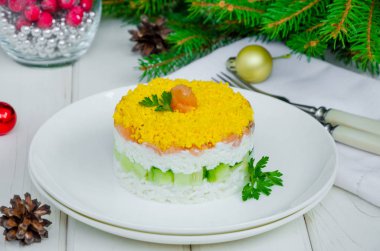 Noel ve Yeni Yıl için beyaz bir tabakta tuzlu somon (kırmızı balık), taze salatalık, pirinç ve yumurta salatası.