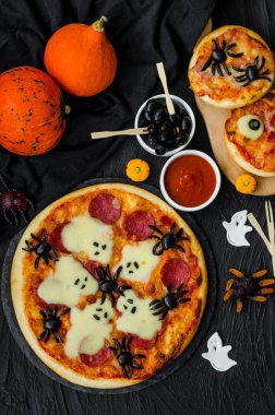 Cadılar Bayramı Pizza Canavarları, peynirli Hayalet ve siyah arka planda zeytin örümceği. Cadılar Bayramı partisi için yemek fikri.
