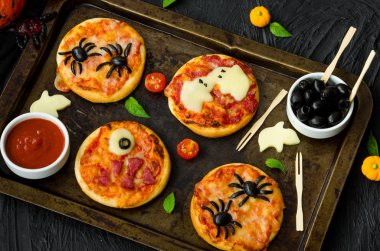 Siyah bir arka plan üzerinde Halloween Mini Pizza Monsters. Örümcek Pizza, Hayalet Pizza, Canavar Pizza. Cadılar Bayramı partisi için gıda fikri.