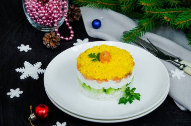Noel için beyaz tabakta tuzlanmış somon salatası (kırmızı balık), taze salatalık, pirinç ve yumurta ve karanlık bir arka planda yeni yıl..