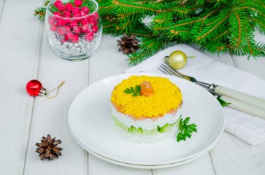 Noel ve Yeni Yıl için beyaz bir tabakta tuzlu somon (kırmızı balık), taze salatalık, pirinç ve yumurta salatası.