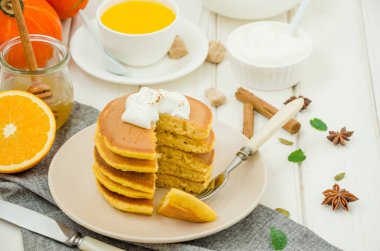 Ballı ve beyaz ahşap arka planda kremalı baharatlı balkabaklı krep yığını. Kırsal tarzda. Güzel kokulu sonbahar kahvaltısı. Cadılar Bayramı için kahvaltı..