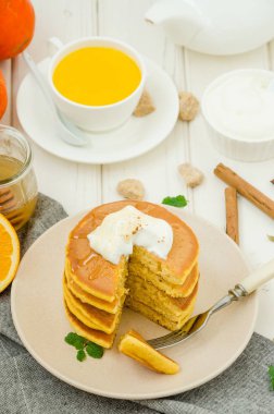 Ballı ve beyaz ahşap arka planda kremalı baharatlı balkabaklı krep yığını. Kırsal tarzda. Güzel kokulu sonbahar kahvaltısı. Cadılar Bayramı için kahvaltı..