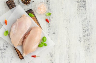 Tahtada çiğ tavuk göğsü, fesleğen ve diğer baharatlarla birlikte ahşap bir arka planda. Sağlıklı yiyecekler. Yatay, boşluğu kopyala