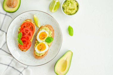 Beyaz beton arka planda püre, haşlanmış yumurta, taze domates ve fesleğen ile tost. Sağlıklı yiyecekler. Yatay, boşluğu kopyala