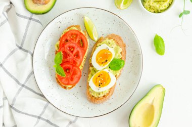 Beyaz beton arka planda püre, haşlanmış yumurta, taze domates ve fesleğen ile tost. Sağlıklı yiyecekler. Yatay, boşluğu kopyala
