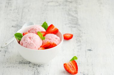 Taze çilekli bir kasede çilekli dondurma ve ahşap zemin üzerinde nane şekeri. Boşluğu kopyala