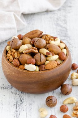 Hafif ahşap arka planda, tahta bir kasede fındık karışımı. Sağlıklı gıda konsepti. Dikey, boşluğu kopyala