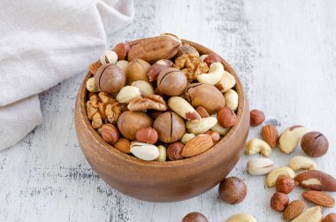 Hafif ahşap arka planda, tahta bir kasede fındık karışımı. Sağlıklı gıda konsepti. Yatay, seçici odak