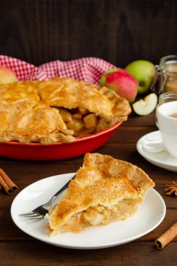 Siyah ahşap arka planda beyaz bir tabakta tarçınlı klasik Amerikan elmalı turtası. Kırsal tarzda. Boşluğu kopyala