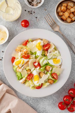 Marullu Sezar salatası, ızgara tavuk göğsü, haşlanmış yumurta, domates, parmesan peyniri ve çimento kaplı seramik tabakta kızarmış ekmek. Üst görünüm