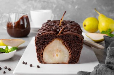 Çikolatalı turta ya da tam armutlu pasta ve gri arka planda çikolata jöleli pasta.