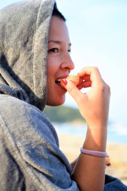 Kumsalda elinde bir şişe su olan genç bir kadın.