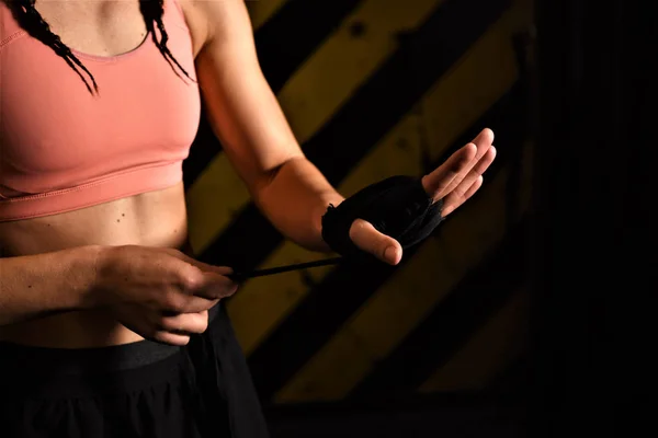 Close-up of a woman doing boxing bandages in a fighting cage