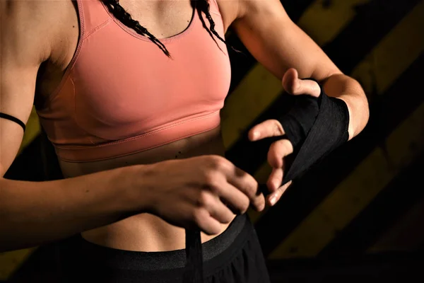 Close-up of a woman doing boxing bandages in a fighting cage