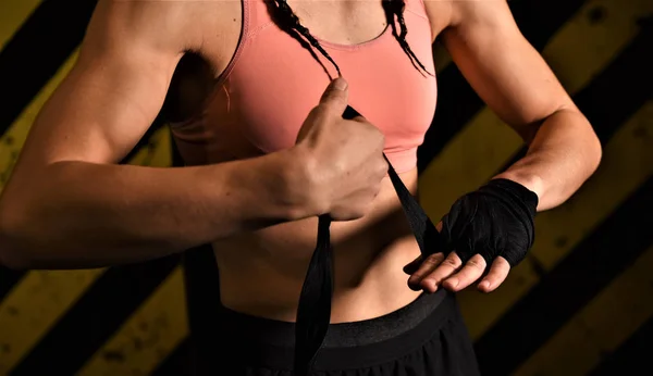 Close-up of a woman doing boxing bandages in a fighting cage
