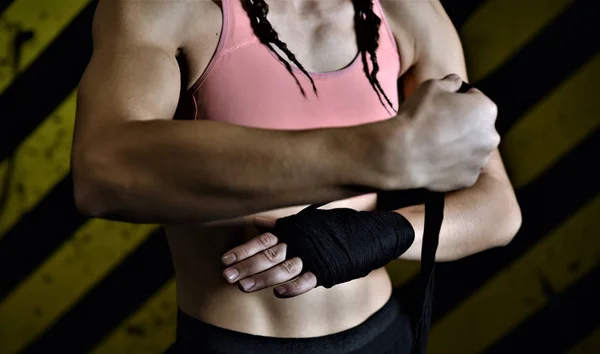 Close-up of a woman doing boxing bandages in a fighting cage