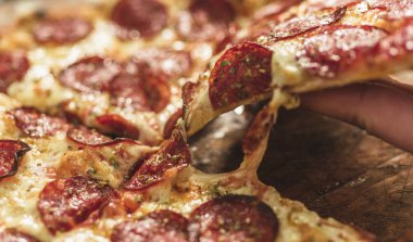 Peynir ve rustik ahşap bir masa üzerinde erime ile sıcak pizza