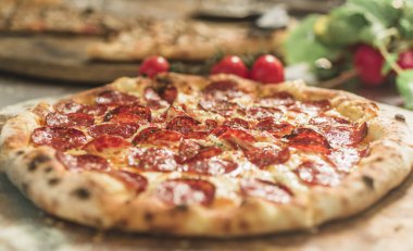 Peynir ve rustik ahşap bir masa üzerinde erime ile sıcak pizza