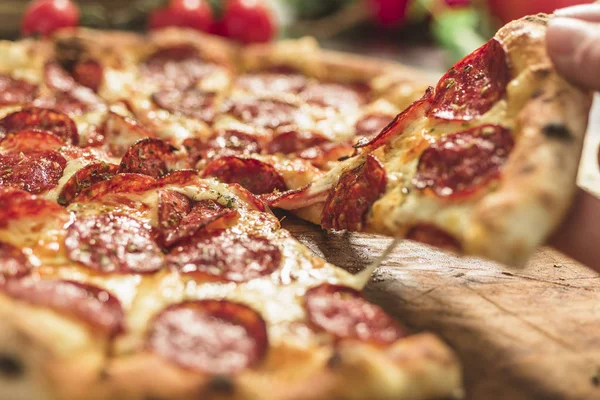 Hot pizza with melting cheese and pepperoni on a rustic wooden table