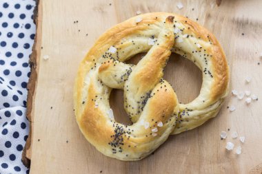 Bir ahşap tahta üzerinde tuz ve haşhaş tohumu ile bir çubuk kraker üzerinde ayrıntılı üstten görünüm