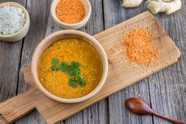 Indian lentil dhal with ginger and fresh coriander on a wooden board top view clipart