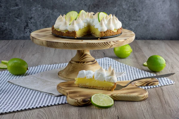 Lime meringue cake with slice cake on confectionery shovel on wooden board