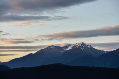 Akşam güneşi Yeni Zelanda'da ışık ile karlı dağlar