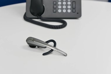 Siyah IP veya arkasında, ofis telefon ile beyaz tabloda kablosuz kulaklık olduğunu