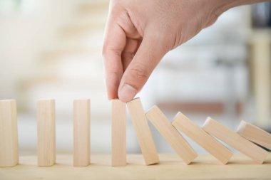 Adam elini tumbling kule iş kavramı için düşme durdurmak için ahşap blok tutuyor