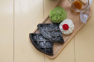 Ahşap çanak içinde kırbaçlanan krem ve şeri ile Kömür waffle ve yeşil çay dondurma Düz yatıyordu