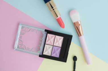 Düz renkli arka plan üzerinde turuncu ruj, pembe yanak fırça ve göz farı palet için yaratıcı kadın Dekoratif kozmetik, kopya alanı ile yatıyordu