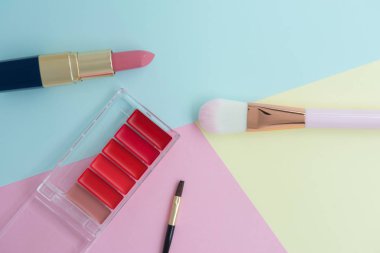 Kopya alanı ile renkli arka plan üzerinde pembe ruj, yanak fırçası ve ruj paleti için kadın dekoratif kozmetik Düz yatıyordu yaratıcı kavramı
