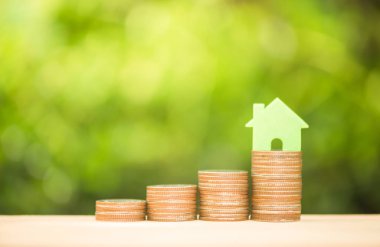 Ev satın alma fonu için para tasarrufu kavramı için sıcak ışık ile büyüyen sikke yığını üzerinde Ev modeli