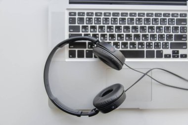 Dizüstü bilgisayarın klavyesindeki telefon kulaklığı yüzüstü yatıyordu