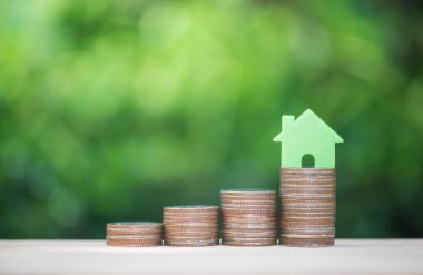 Ev için fon satın tasarruf para kavramı için büyüyen sikke yığını üzerinde ev modeli