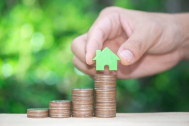 Adam el ev satın alma fonu için para tasarrufu kavramı için büyüyen sikke yığını için ev modeli konur