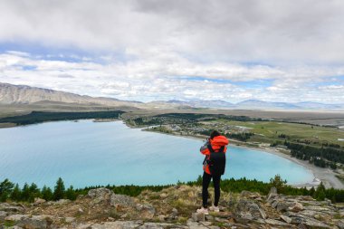 Asyalı kadın gezgin Tekapo Gölü'ne fotoğraf çekiyor 