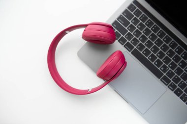 Dizüstü bilgisayar klavyesi üzerinde pembe kablosuz kulaklık flay yatıyordu 