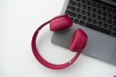 Dizüstü bilgisayar klavyesi üzerinde pembe kablosuz kulaklık flay yatıyordu 